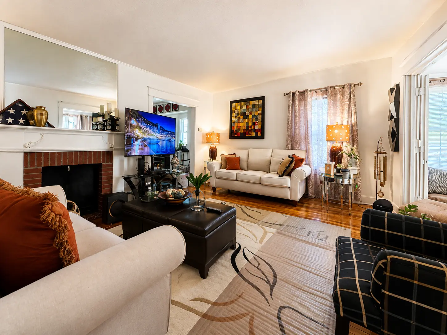 Living room at 3718 Revere Drive with a brick fireplace, hardwood floors, and natural light from front windows