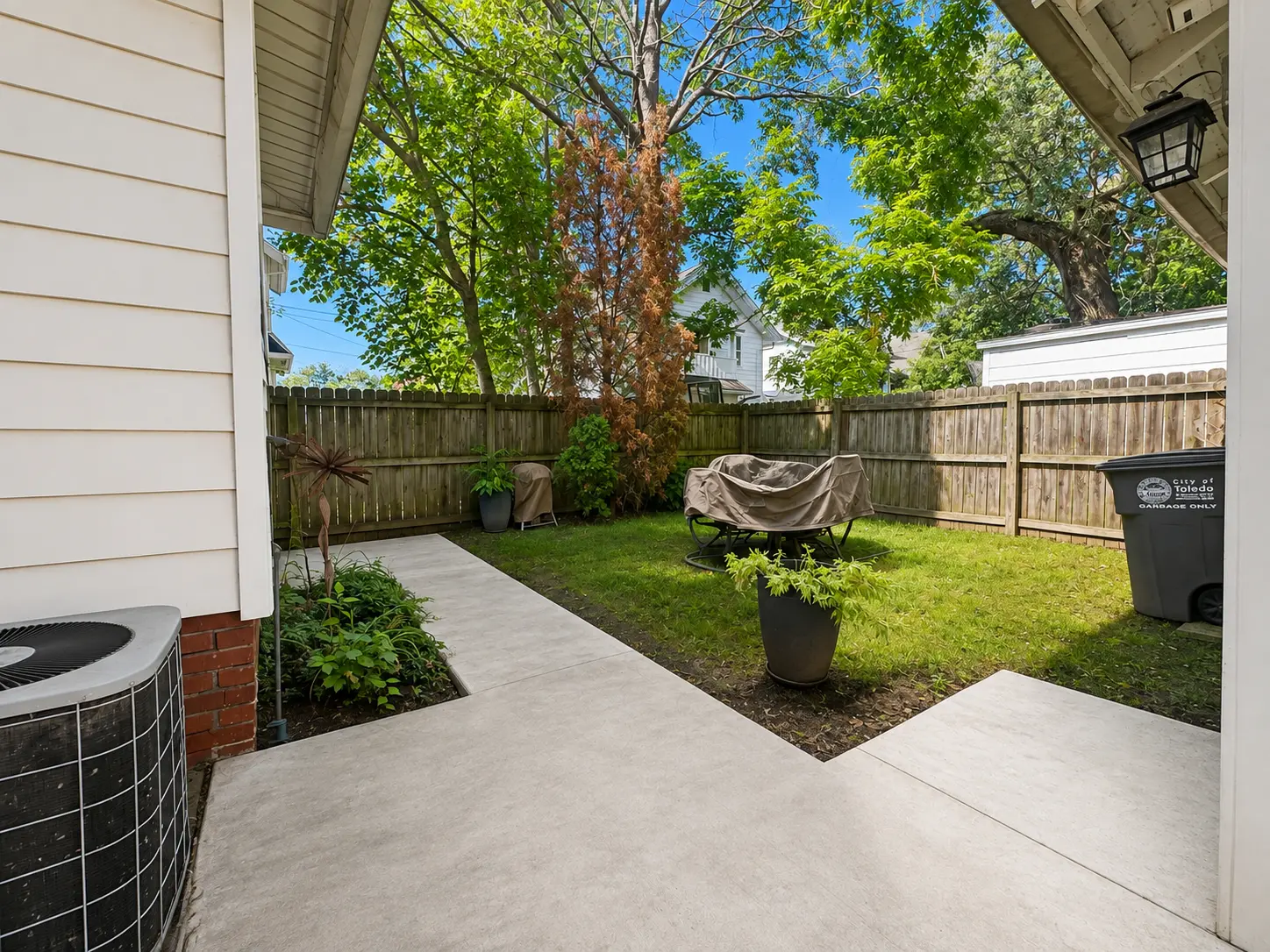 Backyard at 3718 Revere Drive with a concrete patio, privacy fence, landscaping, and mature trees