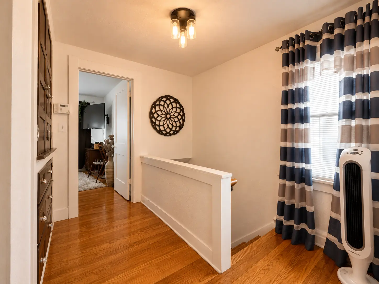 Upstairs landing at 3718 Revere Drive with hardwood floors, built-in linen storage, and a bedroom doorway