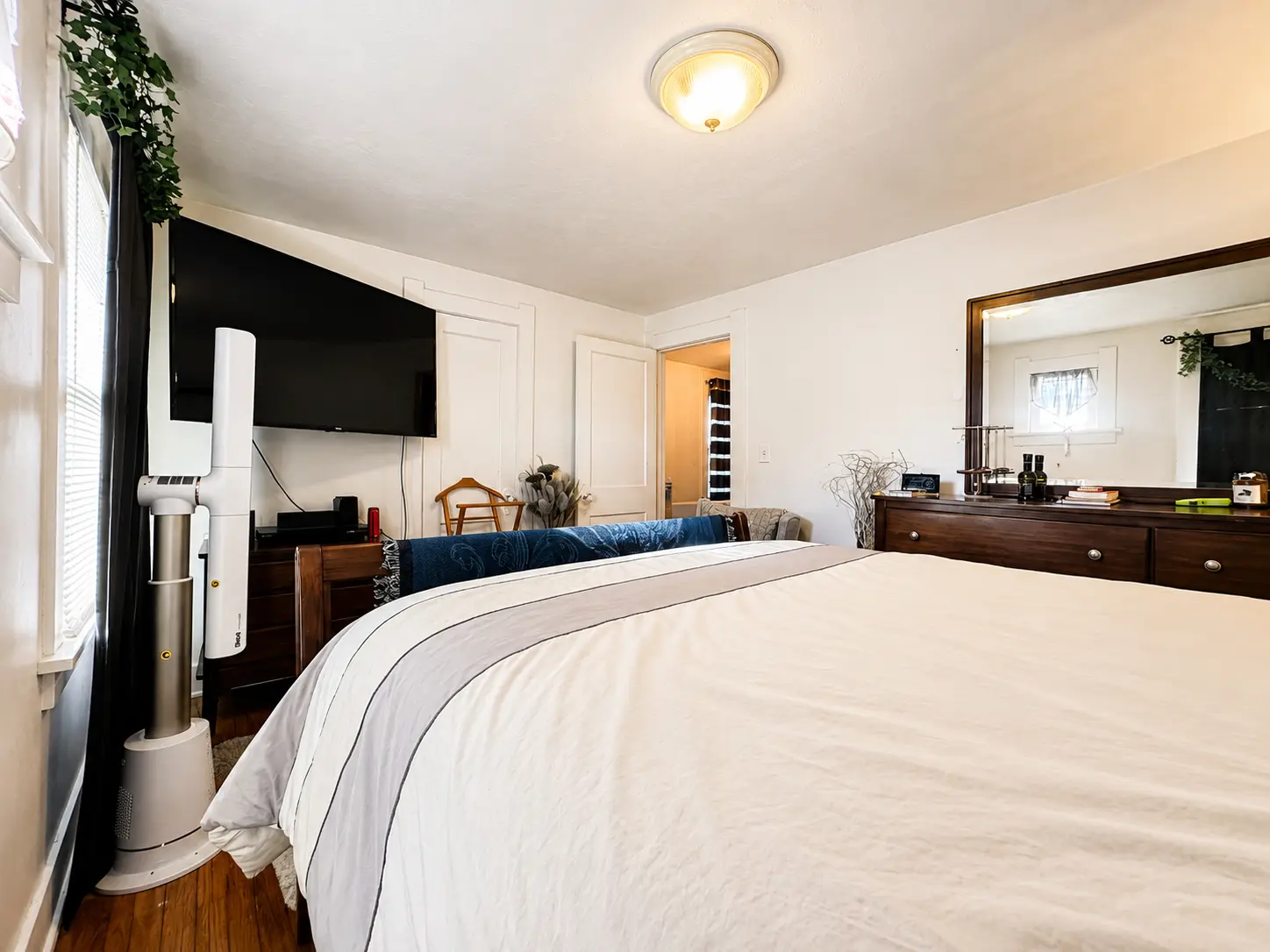 Bedroom at 3718 Revere Drive with a queen bed, wall-mounted television, dresser, and hardwood floors
