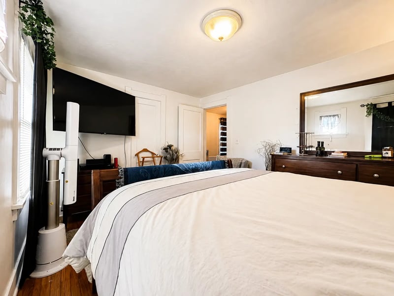 Bedroom at 3718 Revere Drive with a queen bed, wall-mounted television, dresser, and hardwood floors