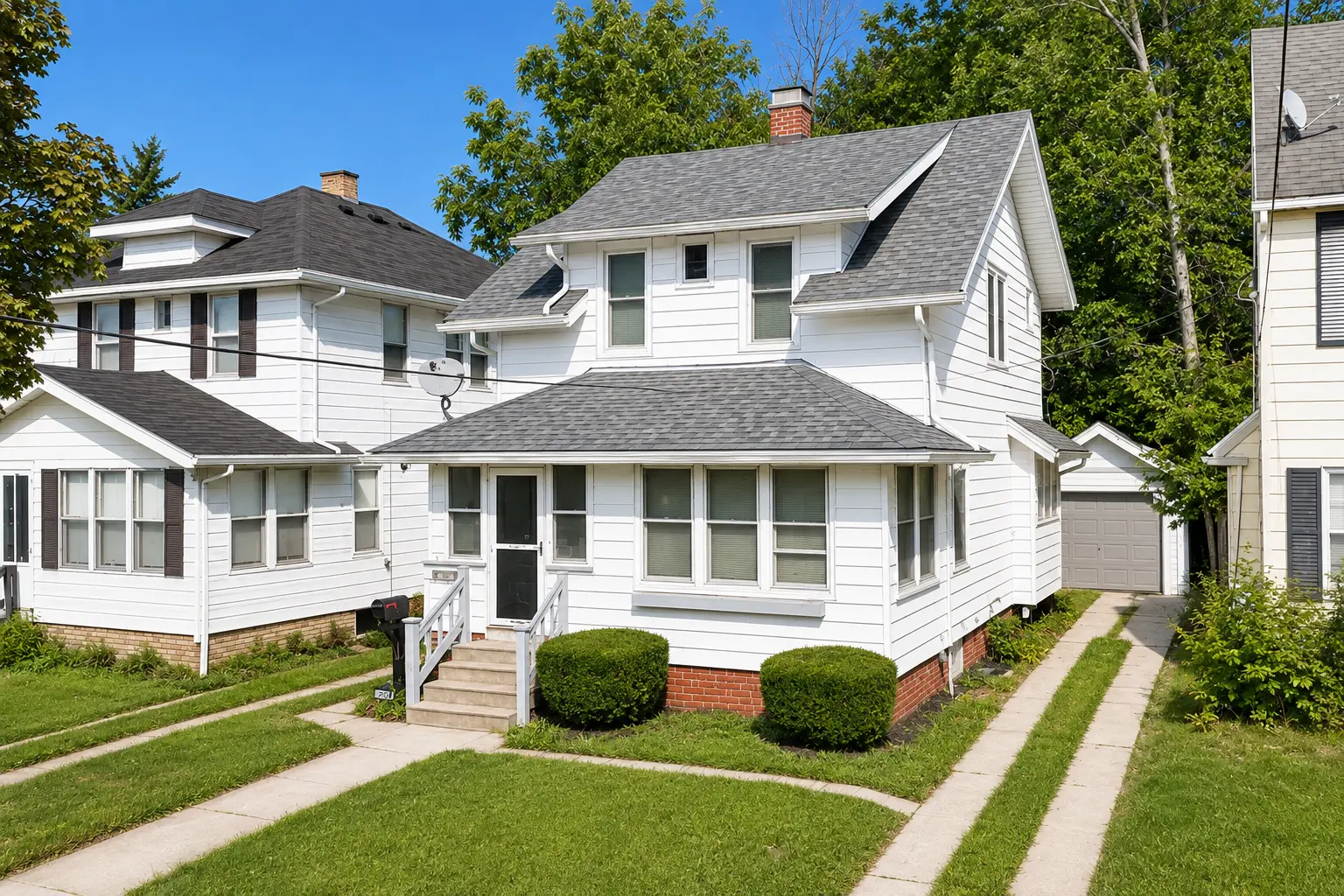 Front exterior of 3718 Revere Drive, a white two-story home in Toledo with a covered front porch and detached garage