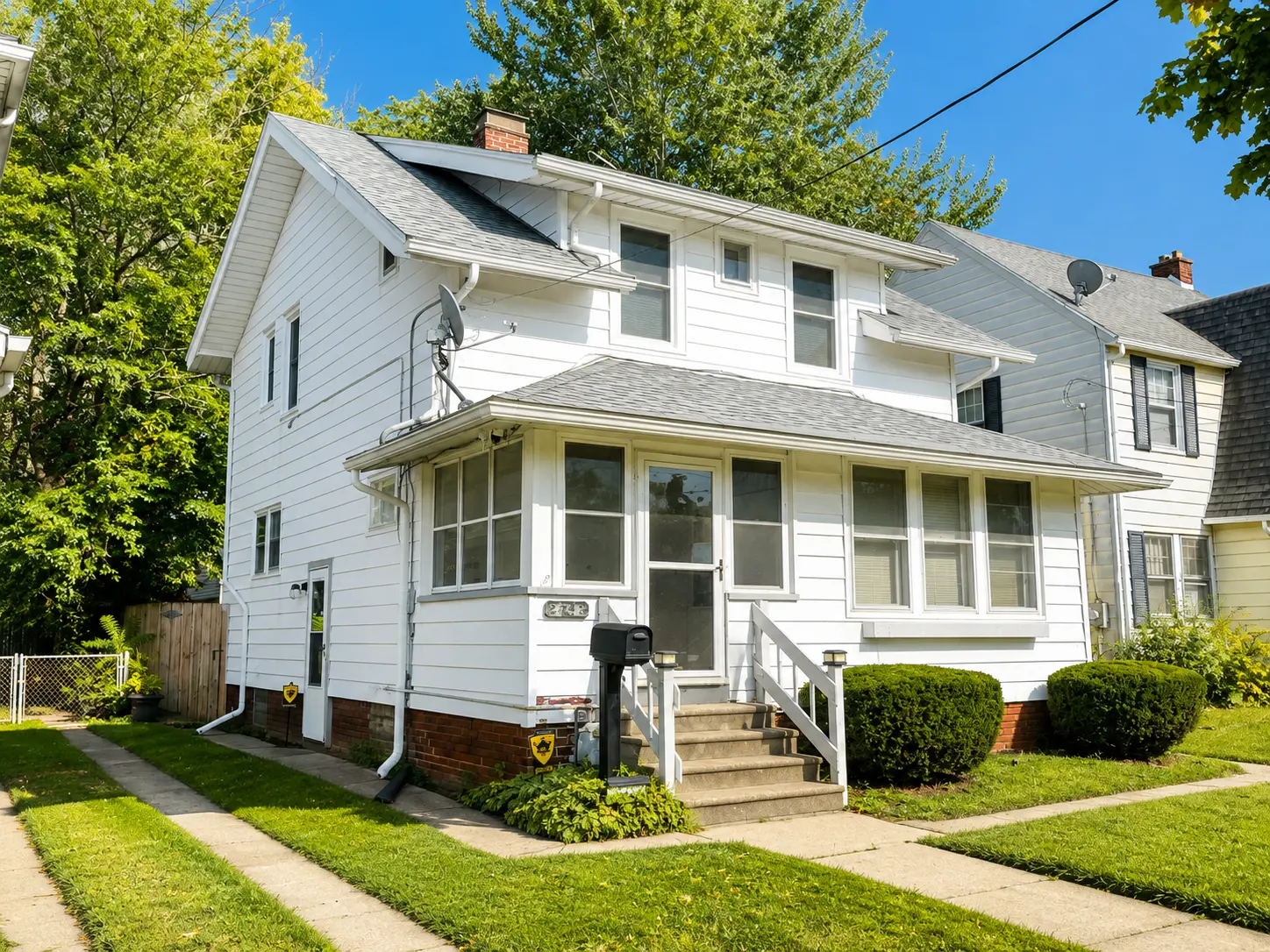 Side view of 3718 Revere Drive showing the enclosed front porch entry and fenced side yard