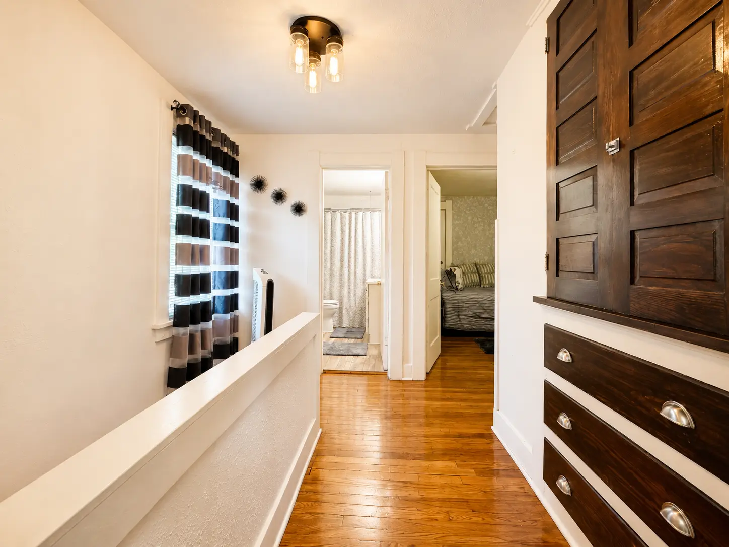 Upstairs hallway at 3718 Revere Drive with built-in drawers and linen cabinet, looking toward the full bath and a bedroom